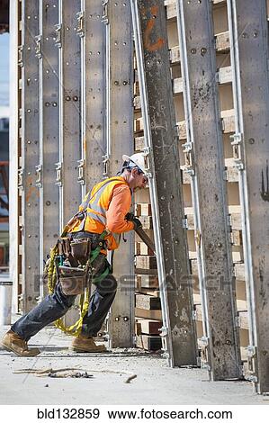 Stock Photo - Caucasian worker pushing wall form at construction site. Fotosearch
