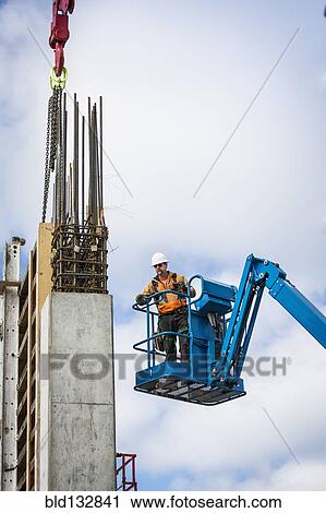 Caucasian worker standing on boom lift on site View Large Photo Image Stock Image - Caucasian worker standing on boom lift on site. Fotosearch