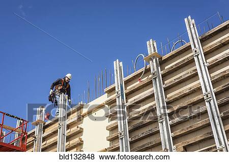 Stock Photo - Caucasian worker walking on concrete wall form. Fotosearch