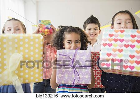 Stock Photograph - Children holding birthday presents at party. Fotosearch