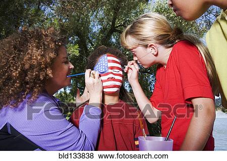 Stock Photo - Children painting American flag on friend's face. Fotosearch