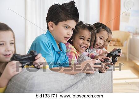 Children playing video games on sofa View Large Photo Image Stock Image - Children playing video games on sofa. Fotosearch