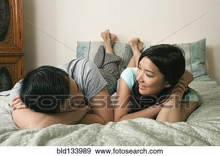 Stock Photo - Chinese couple relaxing on bed. Fotosearch