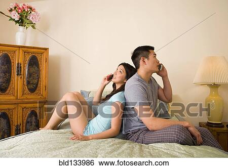 Chinese couple talking on phones in bedroom View Large Photo Image Stock Photograph - Chinese couple talking on phones in bedroom. Fotosearch