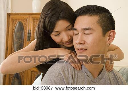 Stock Photo - Chinese woman giving boyfriend shoulder massage. Fotosearch