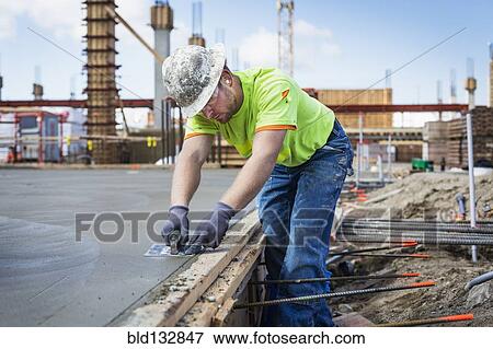 Stock Photo - Construction worker finishing concrete at construction site. Fotosearch