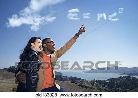 Stock Photo - Couple admiring scientific formula in clouds. Fotosearch
