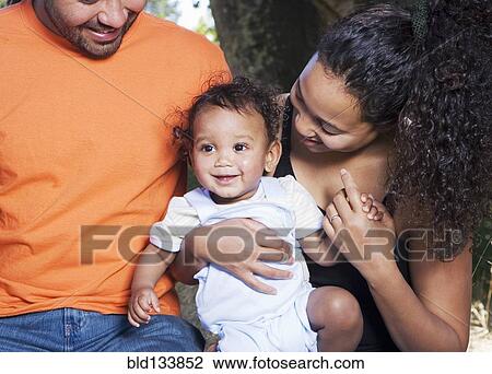 Stock Image - Couple holding baby outdoors. Fotosearch