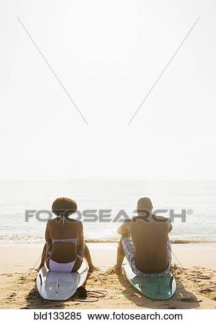 Couple sitting on surfboards on beach View Large Photo Image Stock Photography - Couple sitting on surfboards on beach. Fotosearch