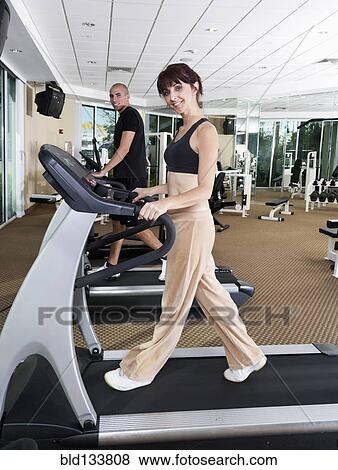 Couple using exercise machines at gym View Large Photo Image Stock Photo - Couple using exercise machines at gym. Fotosearch