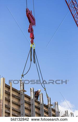 Stock Image - Crane attached to concrete wall form on construction site. Fotosearch