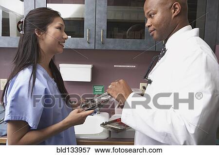 Stock Photo - Dentist and nurse talking in office. Fotosearch