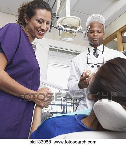Stock Photo - Dentist and nurse talking to patient. Fotosearch