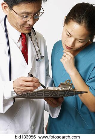 Stock Photograph - Doctor and nurse reading medical charts together. Fotosearch
