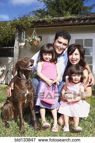 Stock Photo - Family smiling together with dog in backyard. Fotosearch