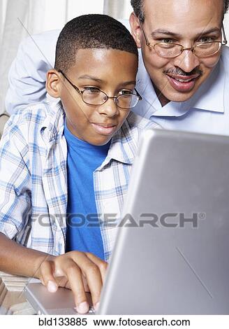 Stock Photography - Father and son using laptop together. Fotosearch
