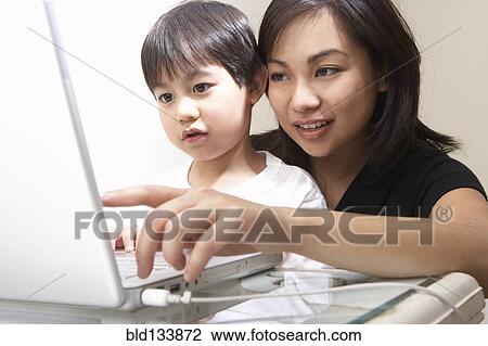Stock Image - Filipino mother and son using laptop together. Fotosearch