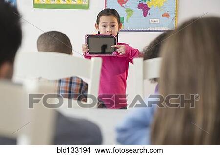 Girl showing digital tablet to classroom View Large Photo Image Picture - Girl showing digital tablet to classroom. Fotosearch