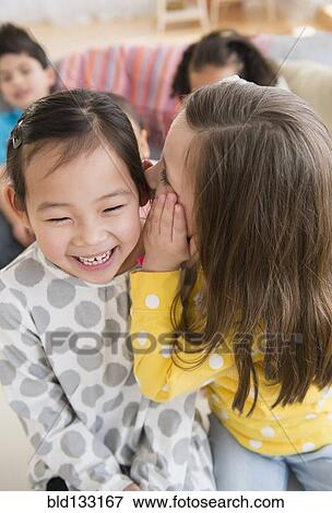 Girl whispering into friend's ear View Large Photo Image Stock Photo - Girl whispering into friend's ear. Fotosearch