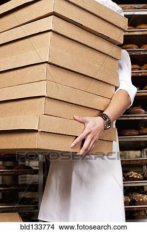 Hispanic baker carrying stack of boxes in bakery View Large Photo Image Picture - Hispanic baker carrying stack of boxes in bakery. Fotosearch