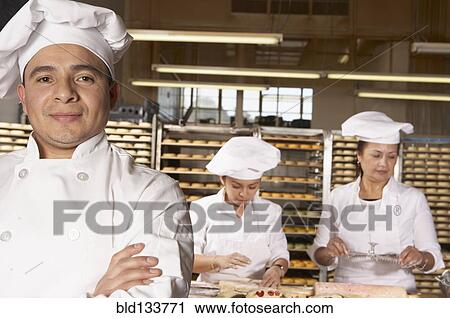 Stock Image - Hispanic bakers working in bakery. Fotosearch