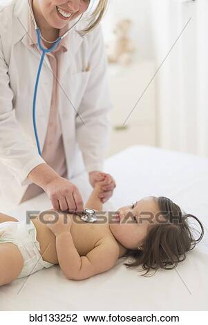 Stock Image - Hispanic doctor listening to toddler's heartbeat. Fotosearch