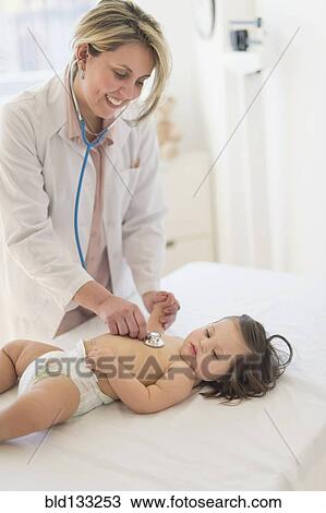 Stock Image - Hispanic doctor listening to toddler's heartbeat. Fotosearch