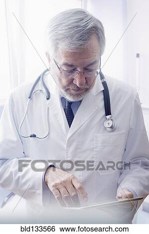 Hispanic doctor reading medical chart in hospital View Large Photo Image Stock Photograph - Hispanic doctor reading medical chart in hospital. Fotosearch