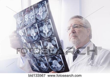 Stock Photo - Hispanic doctor reading x-rays in hospital. Fotosearch