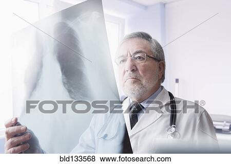 Stock Photo - Hispanic doctor reading x-rays in hospital. Fotosearch