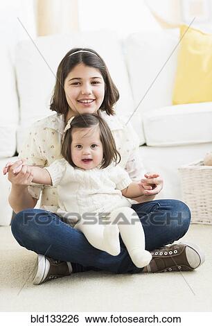Hispanic girl holding toddler sister in living room View Large Photo Image Stock Photograph - Hispanic girl holding toddler sister in living room. Fotosearch