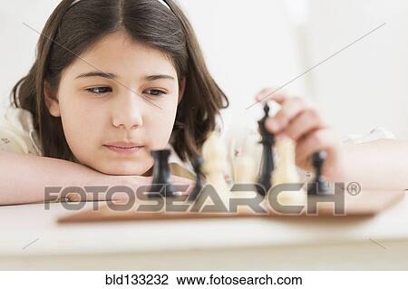Stock Image - Hispanic girl playing chess. Fotosearch