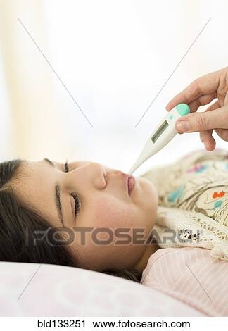 Stock Image - Hispanic girl taking her temperature. Fotosearch