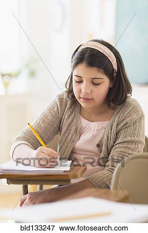 Stock Photo - Hispanic girl taking notes in classroom. Fotosearch