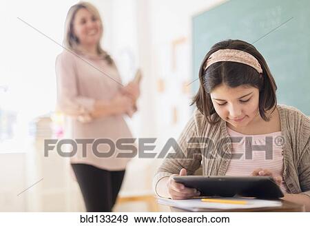 Stock Photo - Hispanic girl using digital tablet in classroom. Fotosearch
