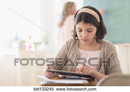 Stock Photography - Hispanic girl using digital tablet in classroom. Fotosearch