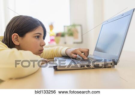 Stock Photograph - Hispanic girl using laptop at desk. Fotosearch