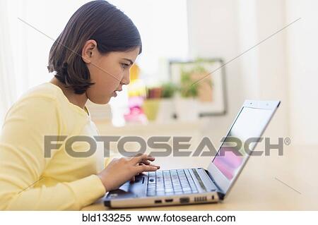 Stock Photography - Hispanic girl using laptop at desk. Fotosearch