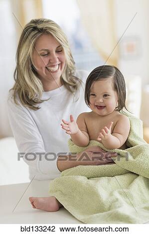 Stock Image - Hispanic mother drying toddler daughter after bath. Fotosearch