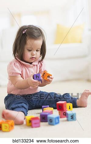 Picture - Hispanic toddler with Down syndrome playing with blocks. Fotosearch
