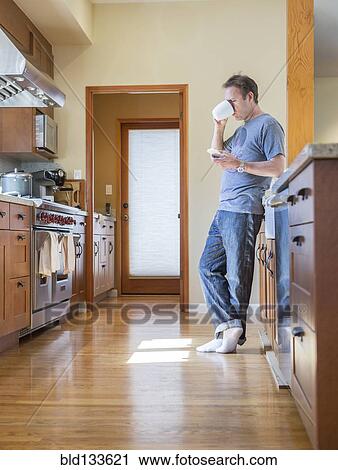Stock Image - Man drinking coffee in kitchen. Fotosearch
