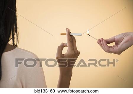 Stock Image - Man lighting woman's cigarette. Fotosearch