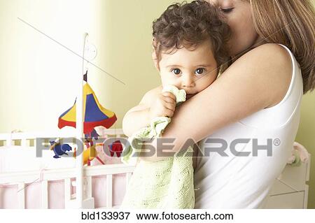 Stock Photo - Middle Eastern woman cradling baby in nursery. Fotosearch