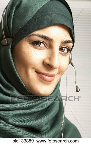 Stock Photo - Middle Eastern woman wearing headset over scarf. Fotosearch
