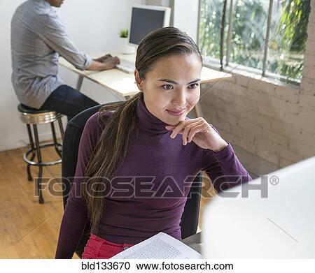 Stock Image - Mixed race architect working in office. Fotosearch