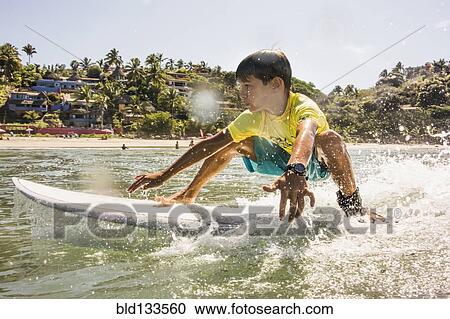 Mixed race boy surfing in ocean View Large Photo Image Stock Image - Mixed race boy surfing in ocean. Fotosearch