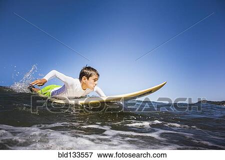 Mixed race boy surfing in ocean View Large Photo Image Stock Photo - Mixed race boy surfing in ocean. Fotosearch
