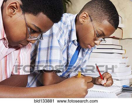 Stock Image - Mixed race boys doing their homework. Fotosearch