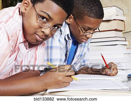 Stock Image - Mixed race boys doing their homework. Fotosearch