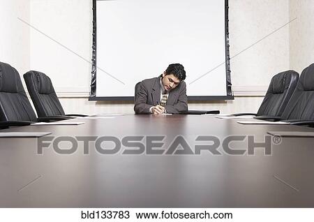 Stock Image - Mixed race businessman sitting at conference table. Fotosearch